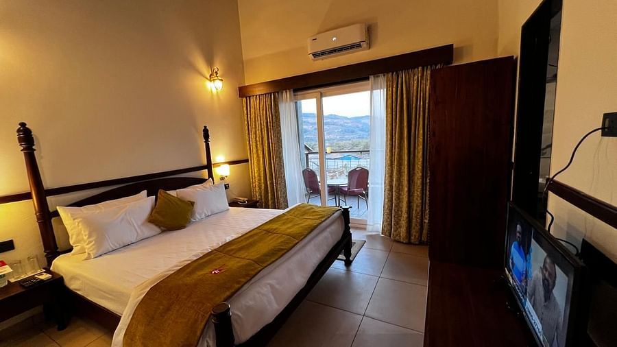 Royal Suite room featuring a large bed with plush bedding and a wide window at Mastiff Grand La Villae Resort, Lonavala